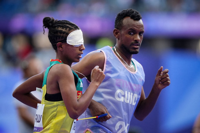 Ethiopia's para-athlete Gate Yayesh Tesfaw (L) and her guide Kindu Sisay Girma (R) compete in the women's 1500m T11 athletic event during the Paris 2024 Paralympic Games at the Stade de France in Saint-Denis, north of Paris, on September 2, 2024.the (Photo by Dimitar Dilkoff/AFP Photo)