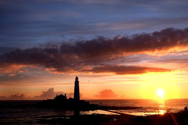 The sun rises beside St Mary's Lighthouse  in Whitley Bay, Tyne and Wear, as the unseasonably cool weather continues on Thursday, April 28, 2016. (Photo by Owen Humphreys/PA Wire)