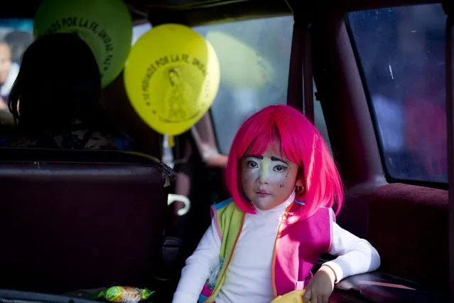 A young clown rides in the back of a car following clowns marching in procession toward the Basilica of Our Lady of Guadalupe in Mexico City, Monday, December 14, 2015. (Photo by Rebecca Blackwell/AP Photo)