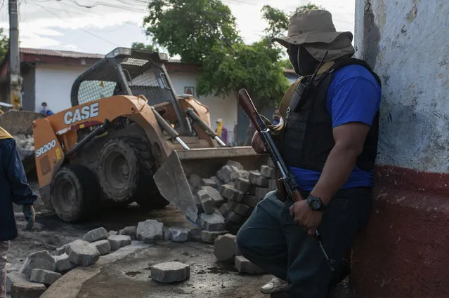 Sandinista militias stand guard at a torn down barricade after police and pro-government militias stormed the Monimbo neighborhood of Masaya, Nicaragua, Tuesday, July 17, 2018. Heavily armed police and militias laid siege to and then retook a symbolically important neighborhood that had recently become a center of resistance to President Daniel Ortega's government. (Photo by Cristibal Venegas/AP Photo)