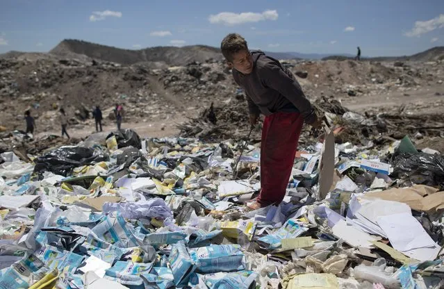 Ronaikel Brito, 16, rummages through empty milk cartons at the Pavia garbage dump on the outskirts of Barquisimeto, Venezuela, Wednesday, March 3, 2021. Waste has been drastically reduced during the pandemic, particularly food from homes, restaurants, and wholesale markets. (Photo by Ariana Cubillos/AP Photo)