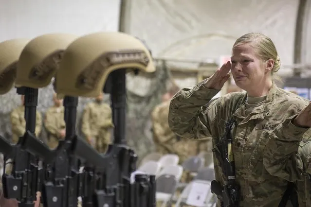 A U.S. service member salutes her fallen comrades during a memorial ceremony for six Airmen killed in a suicide attack, at Bagram Air Field, Afghanistan on Wednesday, December 23, 2015. The deadliest attack in Afghanistan since 2013 killed six U.S. troops on Monday, including a family man from Long Island, New York; a South Texan; a New York City police detective; a Georgia high school and college athlete; an expectant father from Philadelphia; and a major from suburban Minneapolis with ties to the military's LGBT community. (Photo by Tech. Sgt. Robert Cloys/U.S. Air Force via AP Photo)