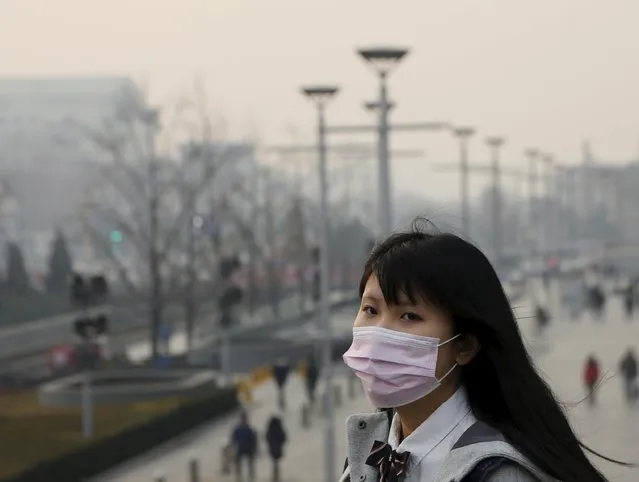 A school girl wearing a protective mask makes her way in a shopping district as China's capital Beijing braces for four days of choking smog starting Saturday, in Beijing, China, December 19, 2015. (Photo by Kim Kyung-Hoon/Reuters)