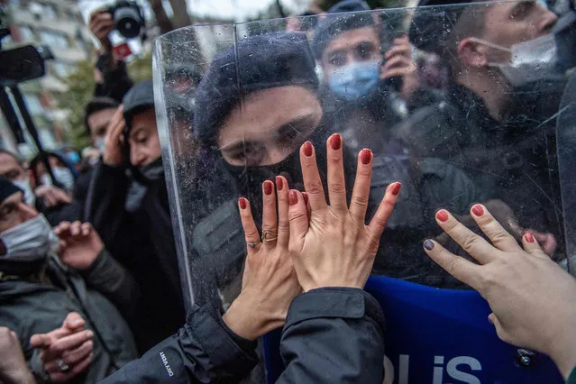 Women protesters clash with Turkish policemen during a demonstration against Turkey's withdrawal from Istanbul Convention, an international accord designed to protect women, in Istanbul, on March 20, 2021. Thousands protested in Turkey on March 20, 2021, calling for President Recep Tayyip Erdogan to reverse his decision to withdraw from the world's first binding treaty to prevent and combat violence against women. (Photo by Bulent Kilic/AFP Photo)