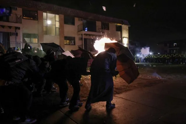 Protesters take cover behind umbrellas amid flash bangs set off by the police while rallying near the Brooklyn Center Police Department, days after Daunte Wright was shot and killed by a police officer, in Brooklyn Center, Minnesota, April 13, 2021. (Photo by Leah Millis/Reuters)