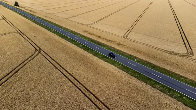 A car passes grain fields at the 'Harz' mountains near Wernigerode, Germany, Wednesday, July 26, 2023. (Photo by Matthias Schrader/AP Photo)