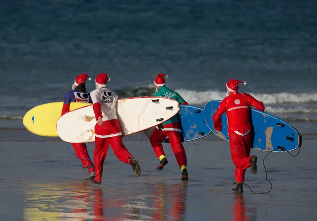 Surfers dressed as Santa run to sea as they compete in a heat during the annual Surfing Santa as part of the Santa Run and Surf 2016 at Fistral Beach in Newquay on December 4, 2016 in Cornwall, . (Photo by Matt Cardy/Getty Images)