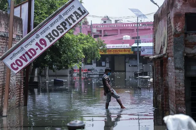 A worker tries to clear water after heavy rains flooded the premises of a COVID-19 hospital being set up at Ghaziabad, outskirts of New Delhi, India, Sunday, May 23, 2021. The hospital is not functional yet. (Photo by Amit Sharma/AP Photo)