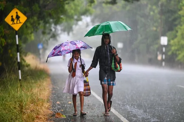 In this photograph taken on August 9, 2023, children make their way along a street during heavy downpour in Kilinochchi. (Photo by Ishara S. Kodikara/AFP Photo)