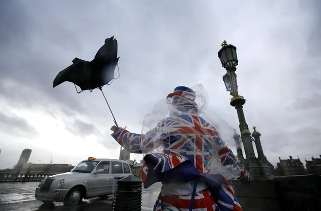 A man giving out leaflets to tourists is blown by the wind in Westminster in London, Monday, February 8, 2016. Winds of nearly 100mph battered Britain after another storm slammed into the south coast bringing fierce gusts and torrential downpours. (Photo by Kirsty Wigglesworth/AP Photo)