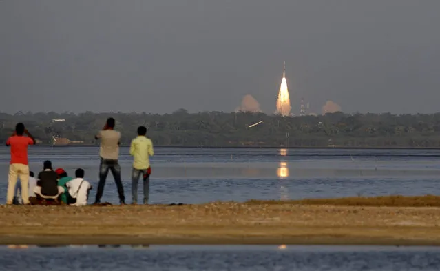 People watch the PSLV-C27 take off carrying India's fourth navigational satellite, in Sriharikota, India, Saturday, March 28, 2015. Indian Space Research Organisation's Polar Satellite Launch Vehicle-C27 successfully lifted off from the Sriharikotta rocket port carrying IRNSS-1D, the fourth satellite of the Indian Regional Navigation Satellite System (IRNSS) that will provide navigation, tracking and mapping services. (Photo by Arun Sankar K./AP Photo)