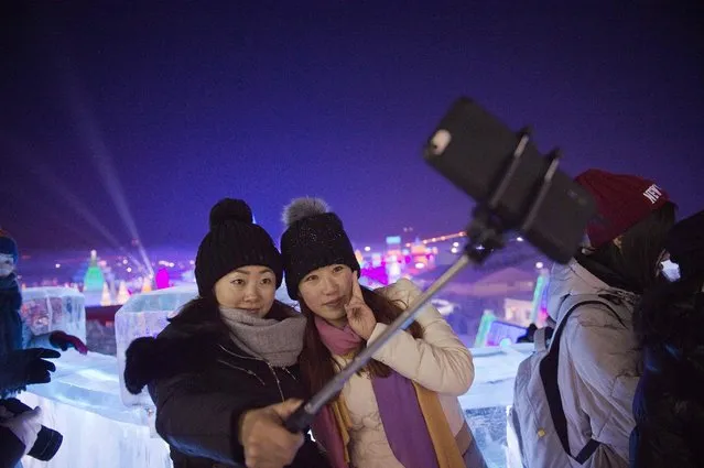 Two young women take a selfie as they visit ice sculptures illuminated by coloured lights at the Harbin Ice and Snow Festival to celebrate the new year in Harbin on January 5, 2017. (Photo by Nicolas Asfouri/AFP Photo)