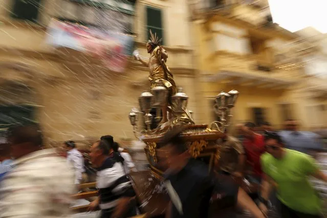 Worshippers run while carrying a statue of the Risen Christ as confetti streams down during an Easter Sunday procession in Cospicua, outside Valletta April 5, 2015. (Photo by Darrin Zammit Lupi/Reuters)