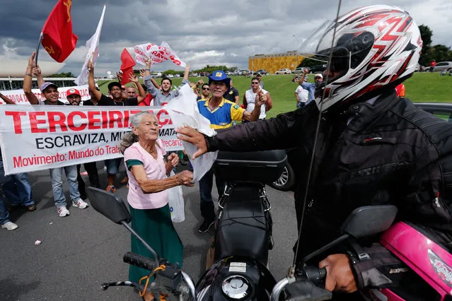 An elder woman hits a motorcycle driver that wants to pass through the march during a protest in Brasilia, Brazil, Tuesday, April 7, 2015. Thousands of workers have staged rallies in 12 cities across Brazil to protest against a proposed law that would allow companies to outsource their labor force. The biggest rally occurred in Brasilia where some 3,000 demonstrators gathered in front of Congress hours before lawmakers were expected to vote on the law. (Photo by Eraldo Peres/AP Photo)
