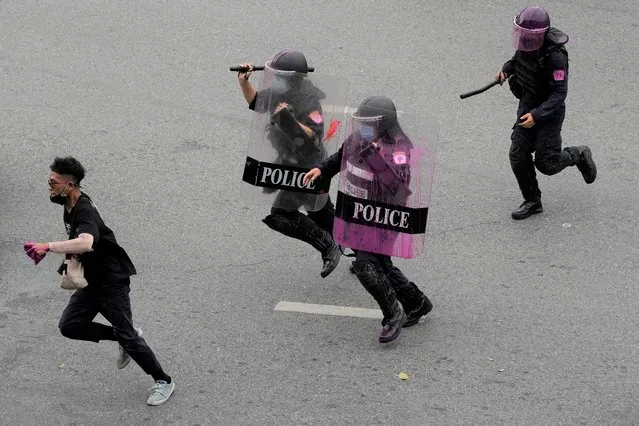 Riot police chase an anti-government protester during protest in Bangkok, Thailand, Wednesday, August 11, 2021. (Photo by Sakchai Lalit/AP Photo)