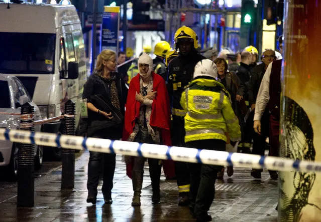 A woman stands bandaged and wearing a blanket  given by emergency services  following an incident at the Apollo Theatre, in London's Shaftesbury Avenue, Thursday evening, December 19, 2013, during a performance at the height of the Christmas season, with police saying there were “a number” of casualties. (Photo by Joel Ryan/AP Photo/Invision)