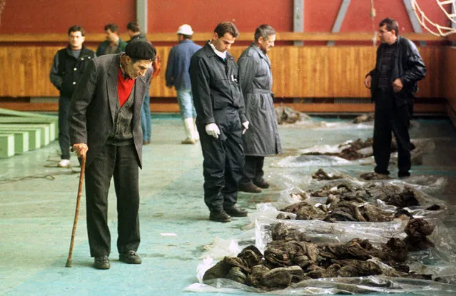 In this October 9, 1996. file photo, Bosnian Muslims trying to recognize their relatives killed by Bosnian Serbs in 1992, inside a sport hall in Kljuc, 160 kms (100mls) north-west of Sarajevo, Bosnia. While it brought an end to the fighting, the Dayton peace agreement baked in the ethnic divisions, establishing a complicated and fragmented state structure with two semi-autonomous entities, Serb-run Republika Srpska and a Federation shared by Bosniak and Croats, linked by weak joint institutions. (Photo by Darko Bandic/AP Photo/File)