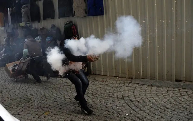 A Kurdish student protestor fires fireworks against Turkish riot policemen on December 24, 2013, in downtown Istanbul, during an anti-government protest marking the second anniversary of a Turkish military air strike aimed at Kurdish rebels that killed 34 civilians working as smugglers at the Turkey-Iraq border in Sirnak. (Photo by Bulent Kilic/AFP Photo)