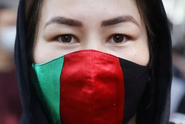 An Afghan woman wearing a mask in the colours of the national flag of Afghanistan looks on during a protest outside an United Nations High Commissioner for Refugees (UNHCR) office to urge the international community to help Afghan refugees, in New Delhi, India, August 23, 2021. (Photo by Anushree Fadnavis/Reuters)