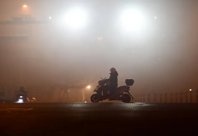 A citizen rides on a road with polluted air in heavy fog in Fuyang city, Anhui province, December 29, 2023. (Photo by CFOTO/Future Publishing via Getty Images)