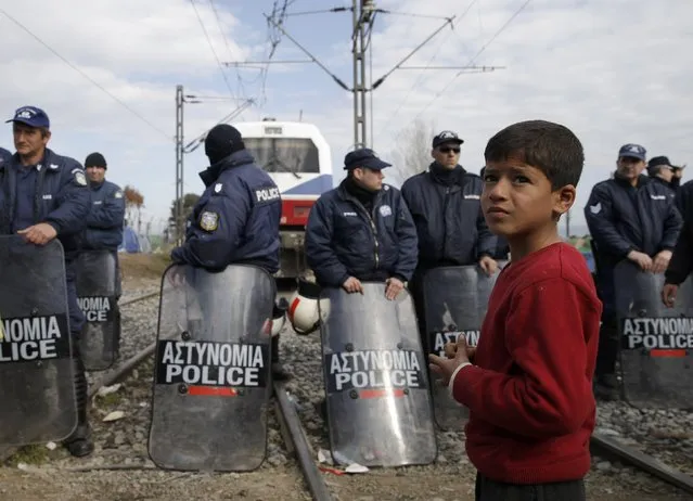 A migrant boy stands next to the riot police as other migrants block the railway track at the Greek-Macedonian border, near the village of Idomeni, Greece March 3, 2016. (Photo by Marko Djurica/Reuters)