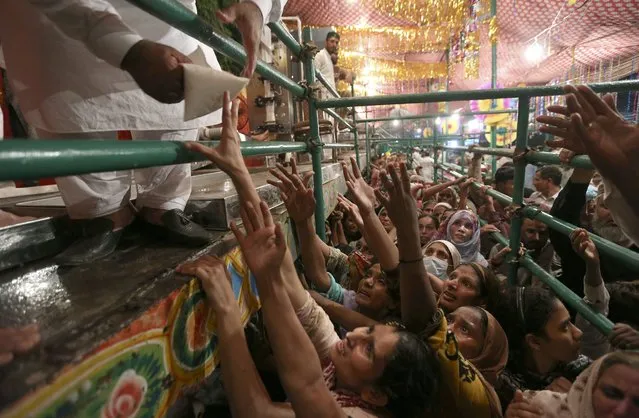 Women jostle to get free milk at a distribution point during the celebrations of the three-day annual festival of famous saint Al-Sheikh Ali Bin Usman Al-Hajveri known as Data Ganjbaksh at his shrine, in Lahore, Pakistan, Sunday, September 26, 2021. Thousands of people traveled from all over Pakistan to attend the celebrations. (Photo by K.M. Chaudary/AP Photo)