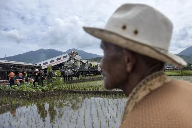 Rescuers inspect the wreckage after the collision between two trains as curious onlookers watch in Cicalengka, West Java, Indonesia, Friday, January 5, 2024. The trains collided on Indonesia's main island of Java on Friday, causing several carriages to buckle and overturn and killing at least a few people, officials said. (Photo by Abdan Syakura/AP Photo)