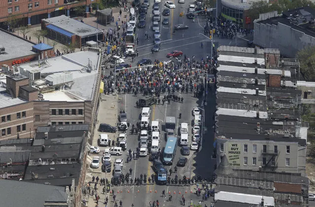 In this aerial photo, police stand in formation near a gathering of protestors at the intersection of North Avenue and Pennsylvania Avenue, Tuesday, April 28, 2015, in Baltimore, a day following unrest that occurred after Freddie Gray's funeral. Gray died from spinal injuries about a week after he was arrested and transported in a Baltimore Police Department van. (Photo by Patrick Semansky/AP Photo)