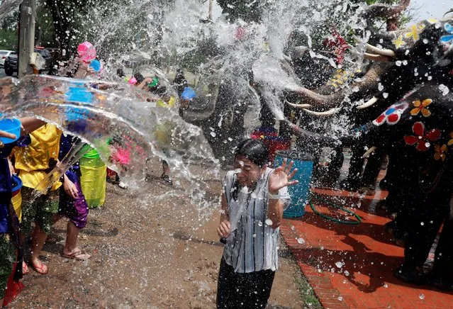 A reporter reacts while reporting as people and elephants play with water in the background as part of celebrations for Songkran in Ayutthaya, Thailand on April 11, 2019. The annual elephant Songkran event is held to promote the tourism industry. Songkran Festival is held also to mark the Thai traditional New Year falling annually on 13 April, and it is celebrated with people splashing water and putting powder on each other faces as a symbolic sign of cleansing and washing away the sins from the past year. (Photo by Soe Zeya Tun/Reuters)