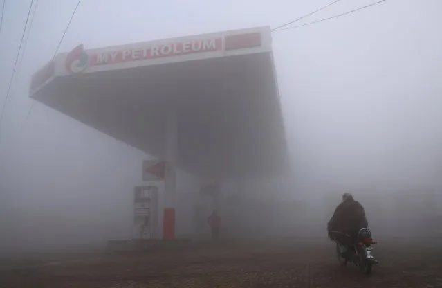 A motorcyclist arrives at a fuel station shrouded in fog on a winter morning on the outskirts of Lahore, Pakistan, on February 5, 2024. (Photo by Thomas Suen/Reuters)
