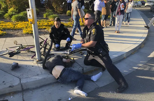 In this photo taken Tuesday, April 23, 2019, provided by Don Draper, a victim of a car crash is offered assistance from police in Sunnyvale, Calif. Draper, a witness to the crash that injured several people, said he was waiting for the light to turn green when a Toyota Corolla plowed through the intersection at high speed. (Photo by Don Draper via AP Photo)
