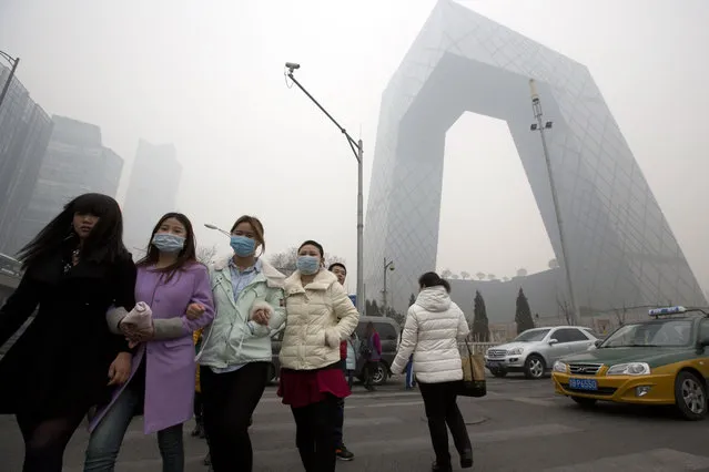 Chinese women wearing masks cross the road near the headquarters of the China Central Television headquarters during a hazy day in Beijing, China, Wednesday, February 26, 2014. (Photo by Ng Han Guan/AP Photo)