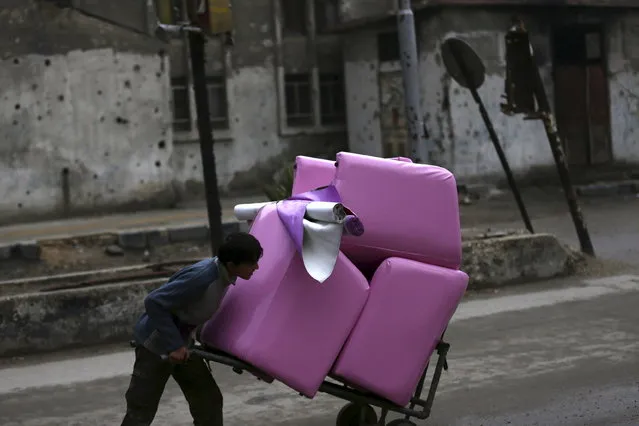 A youth pushes pink couches on a cart in the town of Douma, eastern Ghouta in Damascus, Syria, January 5, 2016. (Photo by Bassam Khabieh/Reuters)