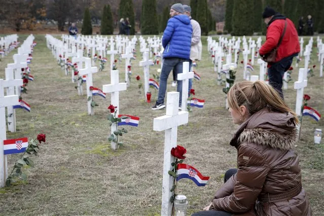 A woman kneels as people lay flowers at Vukovar's memorial cemerety, in Vukovar, eastern Croatia, Thursday, November 18, 2021. Thousands joined memorial events marking the 30th anniversary of the fall of the eastern town of Vukovar to the Serb-led Yugoslav army during Croatia's 1991-95 independence war. (Photo by AP Photo/Stringer)