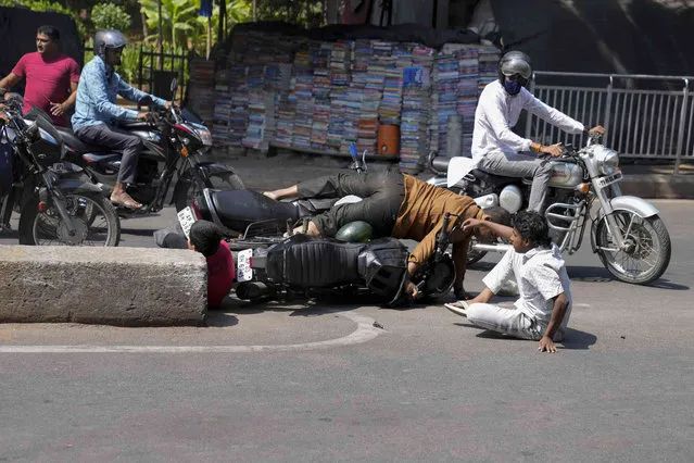 Riders and a pillion rider fall on the ground after two speeding motorcycles collided at a busy road in Hyderabad, India, Friday, March 8, 2024. No major injuries were reported in the accident. (Photo by Mahesh Kumar A./AP Photo)