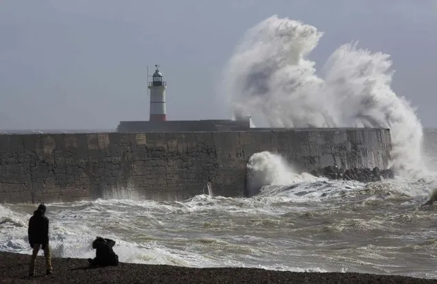 People watch waves crash against the harbour wall at Newhaven in southern Britain March 28, 2016. (Photo by Neil Hall/Reuters)