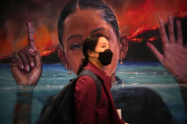 A delegate walks past a mural during day one of COP26 at SECC on October 31, 2021 in Glasgow, Scotland. The procedural opening ceremony marks the start of negotiations at COP26 and the appointment of its President Alok Sharma, the handover of the Presidency from COP25 President Carolina Schmidt and remarks from Alok Sharma and Executive Secretary of the United Nations Framework Convention on Climate Change Patricia Espinosa. (Photo by Christopher Furlong/Getty Images)