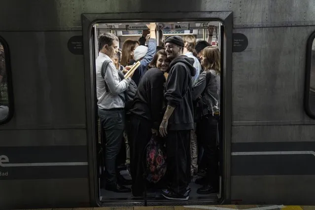 A smiling couple squeeze into a subway car packed with commuters, in Buenos Aires, Argentina, April 12, 2024. (Photo by Rodrigo Abd/AP Photo)