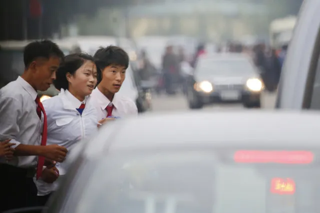 In this October 8, 2015, photo, students watch the traffic as they cross a street in Pyongyang, North Korea. The streets of Pyongyang are more crowded than ever, but Pyonghwa Motors, North Korea's only passenger car company, whose sole factory was designed to produce as many as 10,000 cars a year, appears to be stuck in neutral. (Photo by Charles Dharapak/AP Photo)