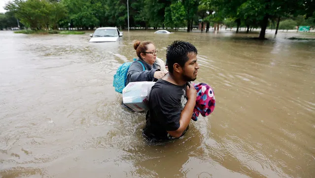 Margarita Uribe, left, and her husband, Juan Juarez, wade through floodwaters as they evacuate their flooded apartment complex Monday, April 18, 2016, in Houston. (Photo by David J. Phillip/AP Photo)