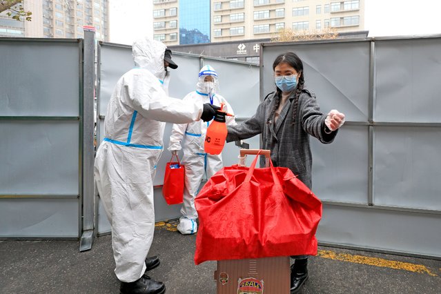 A medical worker wearing personal protective equipment (PPE) sprays disinfectant to a resident, who completed the quarantine period, at the entrance of a residential community under closed-off management on January 6, 2022 in Xi an, Shaanxi Province of China. (Photo by VCG/VCG via Getty Images)