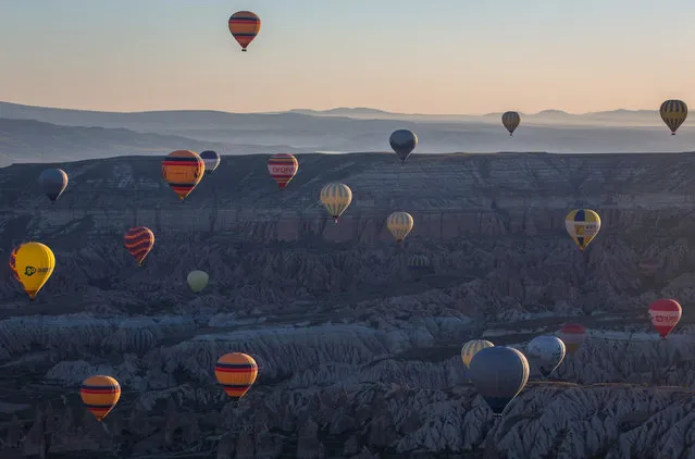 Hot air balloons are seen over rock formations near the town of Goreme on April 17, 2016 in Nevsehir, Turkey. Cappadocia, a historical region in Central Anatolia dating back to 3000 B.C is one of the most famous tourist sites in Turkey. Listed as a World Heritage Site in 1985, and known for its unique volcanic landscape, fairy chimneys, large network of underground dwellings and some of the best hot air ballooning in the world, Cappadocia is preparing for peak tourist season to begin in the first week of May. (Photo by Chris McGrath/Getty Images)