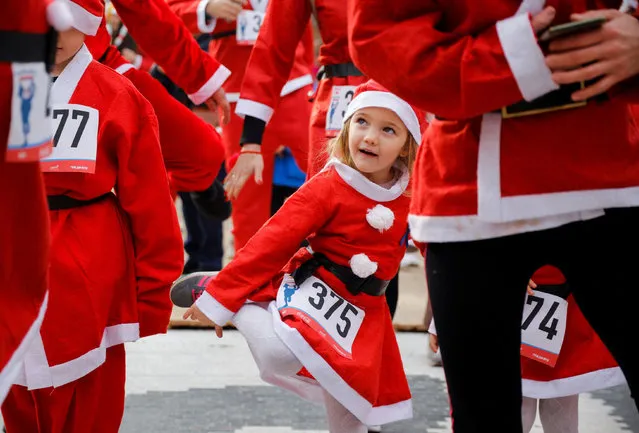 A kid dressed as Santa Claus dances along with others during the annual Santa race competition in Skopje, North Macedonia, December 26, 2021. (Photo by Ognen Teofilovski/Reuters)
