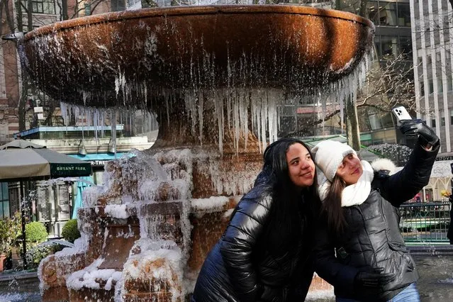 People pose for a photo in front of the fountain in Bryant Park in the Manhattan borough of New York City, New York, U.S., January 11, 2022. (Photo by Carlo Allegri/Reuters)