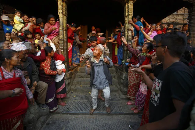 A priest ringing a bell walks out from the temple of God Bhairab during the Bisket festival at Bhaktapur April 10, 2014. The festival, which runs for more than a week and coincides with the Nepalese New Year, involves devotees offering prayers and the pulling of two chariots, one carrying the idol of God Bhairab and the other with the idol of Goddess Bhadrakali, around the ancient city of Bhaktapur. (Photo by Navesh Chitrakar/Reuters)