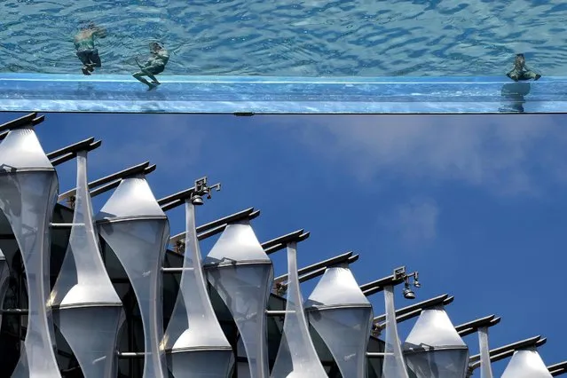Residents relax in the Embassy Gardens Sky Pool, a suspended transparent acrylic swimming pool, with the U.S. Embassy building seen behind, London, Britain on May 27, 2021. (Photo by Toby Melville/Reuters)