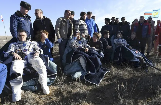 The International Space Station (ISS) crew members NASA astronaut Shane Kimbrough (L) and cosmonauts Sergey Ryzhikov (C) and Andrey Borisenko of the Russian space agency Roscosmos, surrounded by ground personnel, rest shortly after the landing of Russia's Soyuz MS-02 space capsule near the town of Dzhezkazgan (Zhezkazgan), Kazakhstan, April 10, 2017. (Photo by Kirill Kudryavtsev/Reuters)