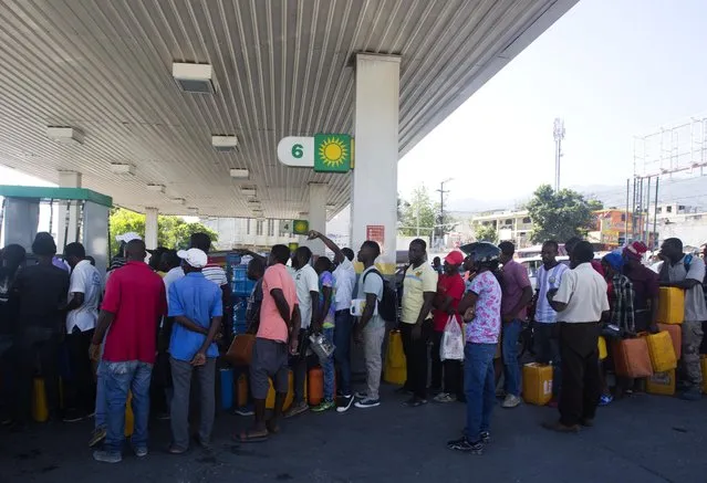 In this April 10, 2019 photo, people line up at a gas station to fill containers with fuel, in Port-au-Prince, Haiti. As Venezuelan President Nicolás Maduro's government has struggled with plunging petroleum production and a cratering economy, the South American country has been forced to stop sending billions in subsidized oil to countries throughout Central America and the Caribbean, including Haiti. (Photo by Dieu Nalio Chery/AP Photo)