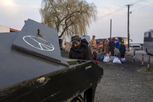 German pianist of Italian descent Davide Martello, plays piano at the border crossing in Medyka, Poland, on Wednesday, March 16, 2022, for people who fled the war from Ukraine, background. (Photo by Petros Giannakouris/AP Photo)