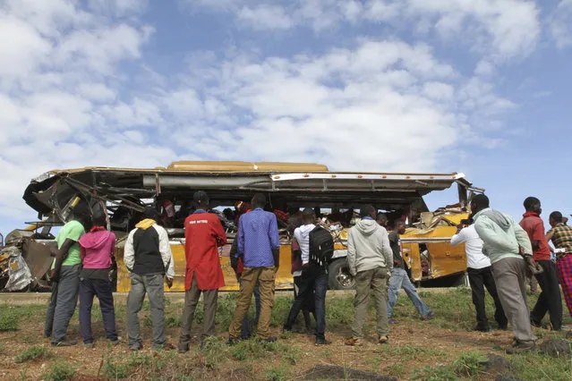 Kenyans look at the wreckage of a Buscar Bus Company vehicle that was involved in a road accident at Kambuu area in Makueni, along the Nairobi-Mombasa highway Tuesday, April 25. 2017. Kenyan police say 27 people have been killed in a collision between a passenger bus and a trailer truck. (Photo by AP Photo/Stringer)